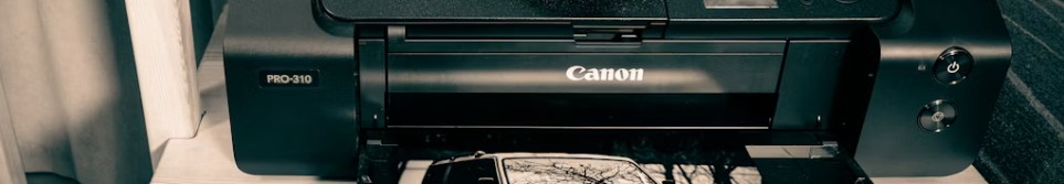 Canon-skrivare på skrivbord som skriver ut ett foto.